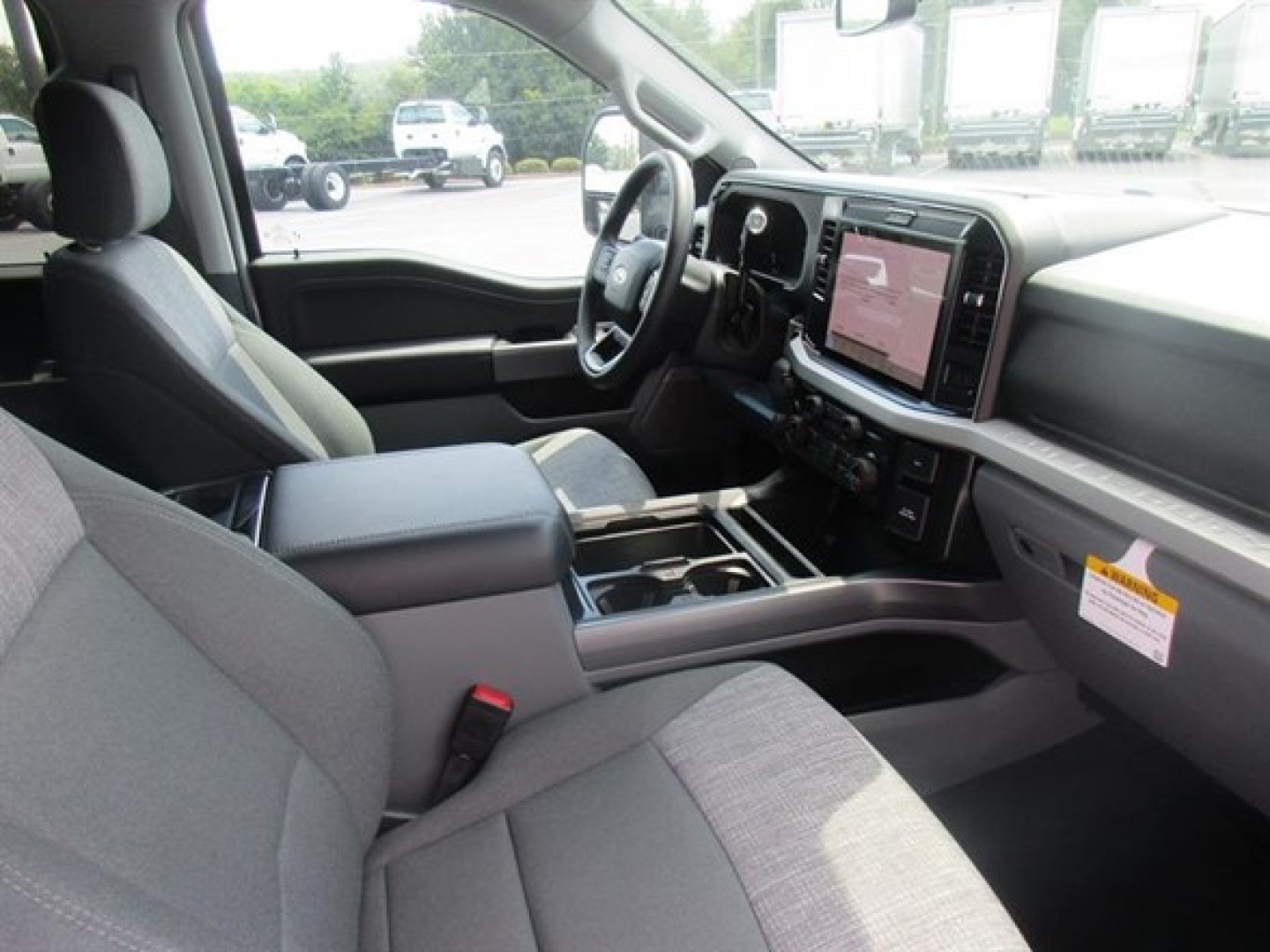Ford F-250 interior driver seat and dashboard view showing center touchscreen and gear selector with gray cloth seats.