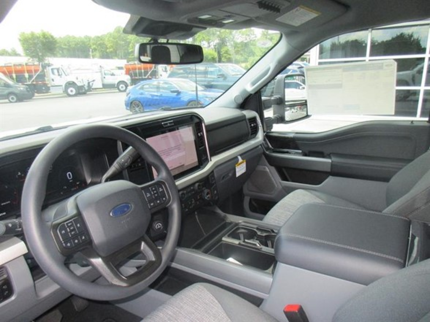 Interior of 2026 Ford F-250 2WD pickup showing steering wheel, dashboard with touchscreen, center console, and front seats.
