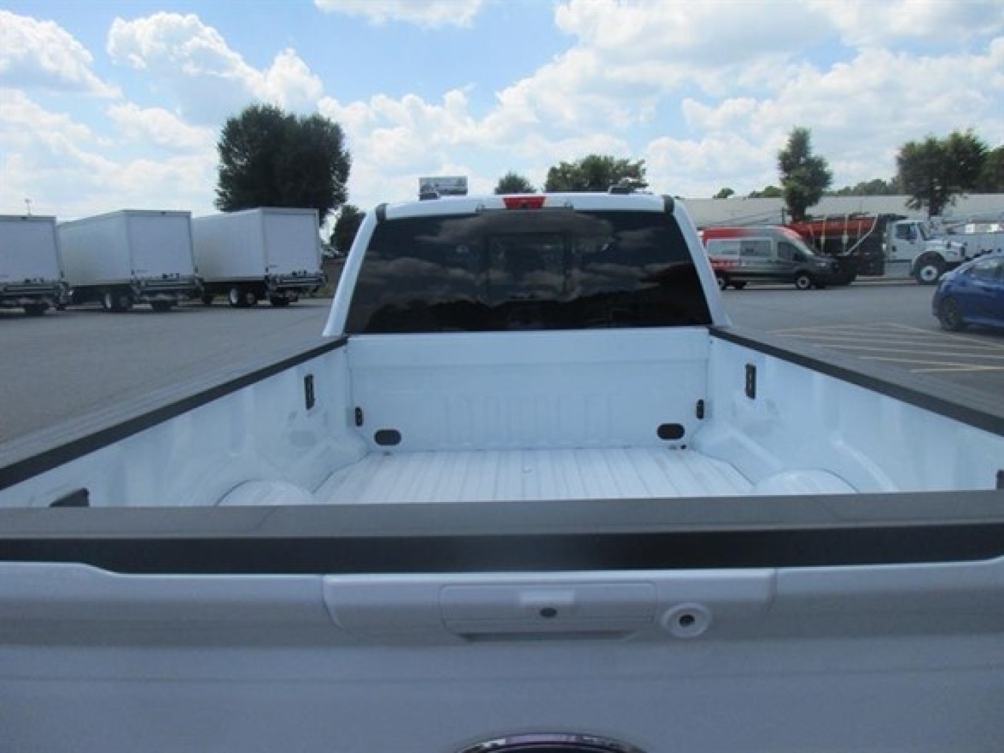 Pickup bed view of a white 2026 Ford F250 with empty cargo area and dark rear window.