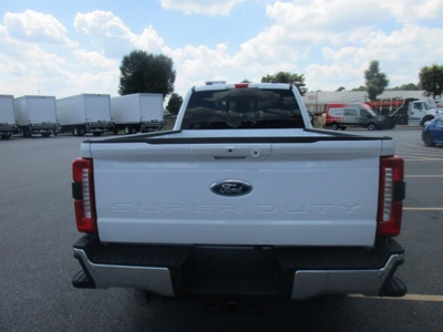 Ford F-250 Super Duty rear view showing tailgate with Ford emblem and embossed 'Super Duty' text in white model, truck bed in a parking lot.