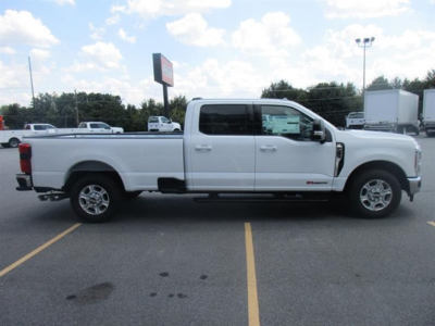 Ford F-250 pickup truck side view in white, extended crew cab, long bed, in a dealership lot.