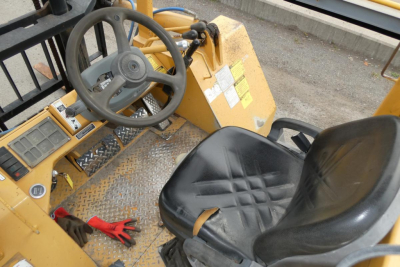 Forklift operator seat and steering wheel area of a yellow Master Craft lift showing dashboard controls and textured metal floor.