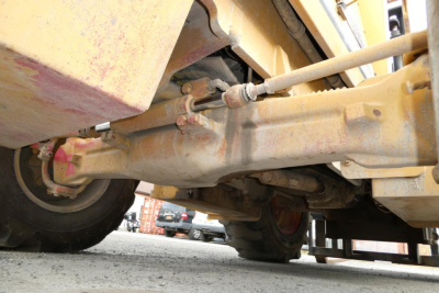 Truck lift axle underside showing hydraulic lines and drivetrain components.
