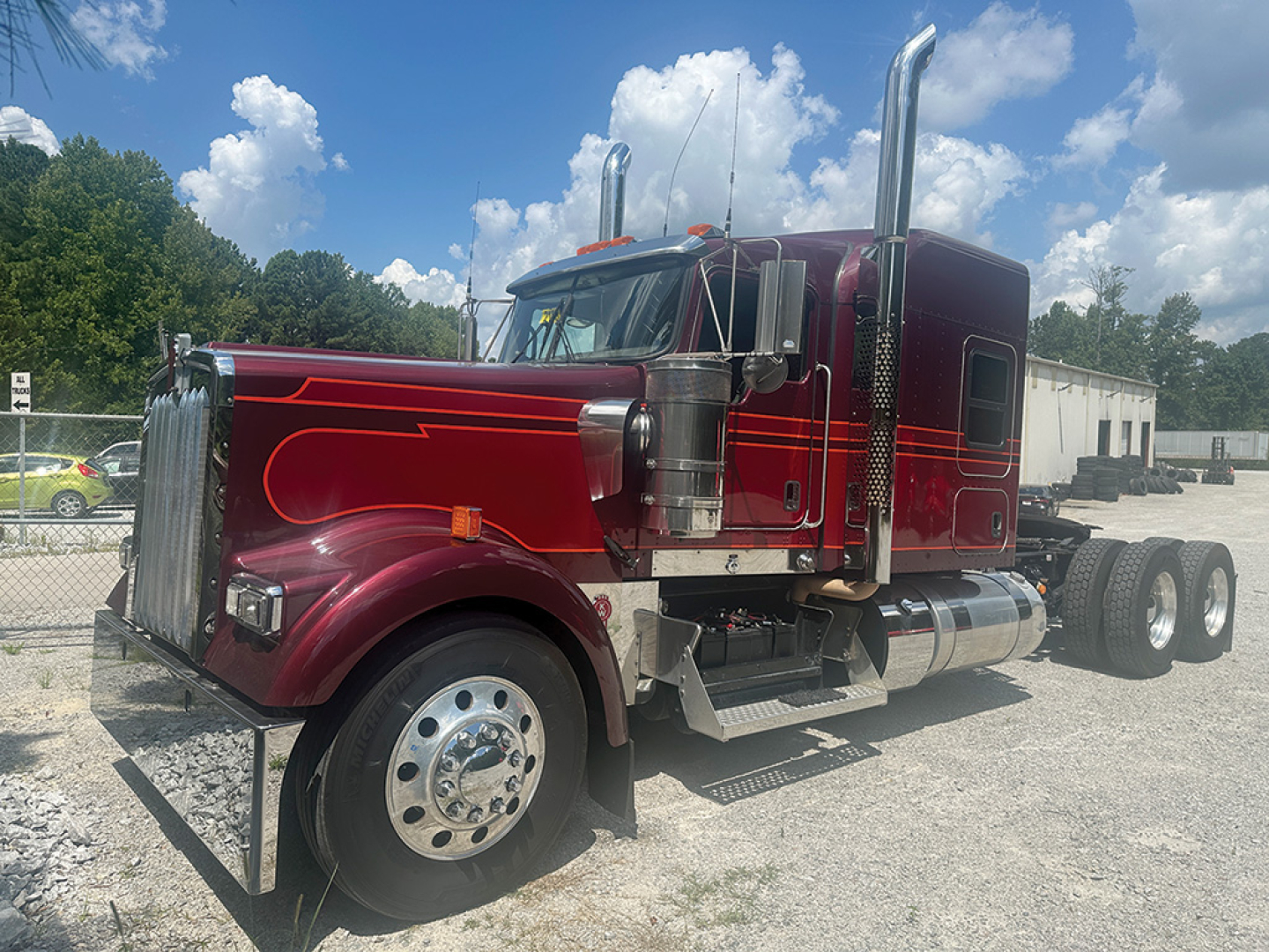 Kenworth W-900L AeroCab truck side view showing chrome exhaust stacks and maroon cab with chrome accents.