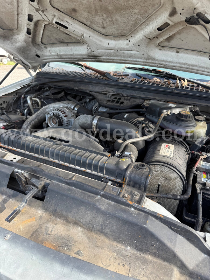 Ford F-550 2006 engine bay view showing air intake, serpentine belt, and various hoses. Hood open, dusty, with engine components visible.