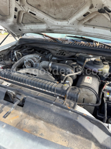 Ford F-550 2006 engine bay view showing air intake, serpentine belt, and various hoses. Hood open, dusty, with engine components visible.