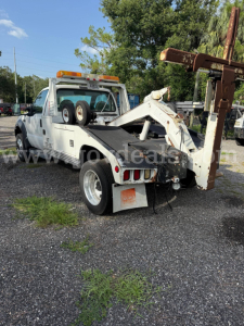 Ford F-550 tow truck rear view showing hydraulic boom and winch, with orange light bar, dual rear wheels, and VIN plate edge visible.