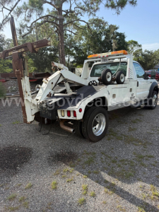 Truck bed tow rig on a white 2006 Ford F-550 in-service with a folding tow boom and warning light bar.