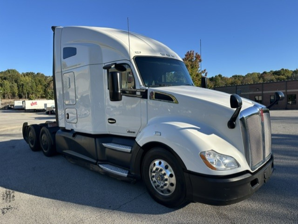 Kenworth T680 truck cab side view. Visible text on truck includes a badge on the hood and mirrors; no legible model text readable in this image.