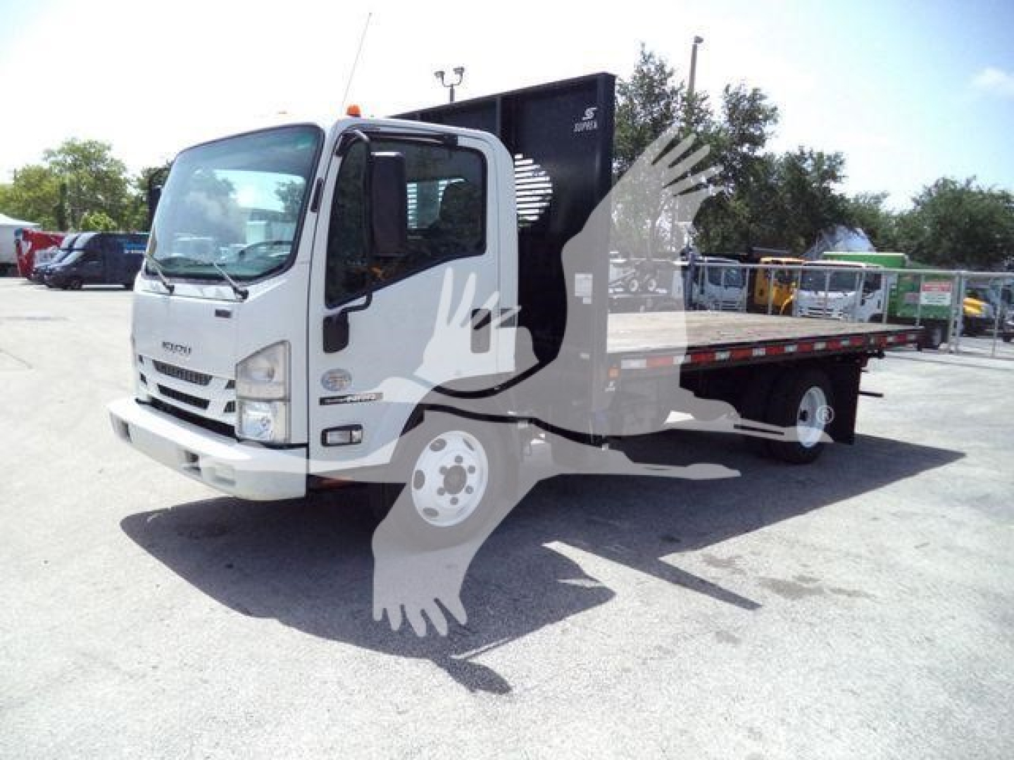 Isuzu NPR/flatbed truck in view with white cab and flatbed dump body, side profile.