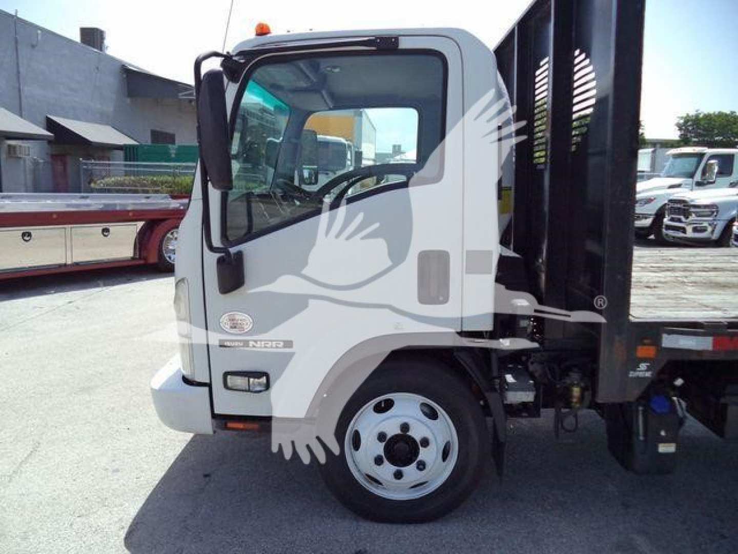 Isuzu NPR truck cab with flatbed; text on door shows Isuzu logo and NPR badge; no specific fluid labels visible.