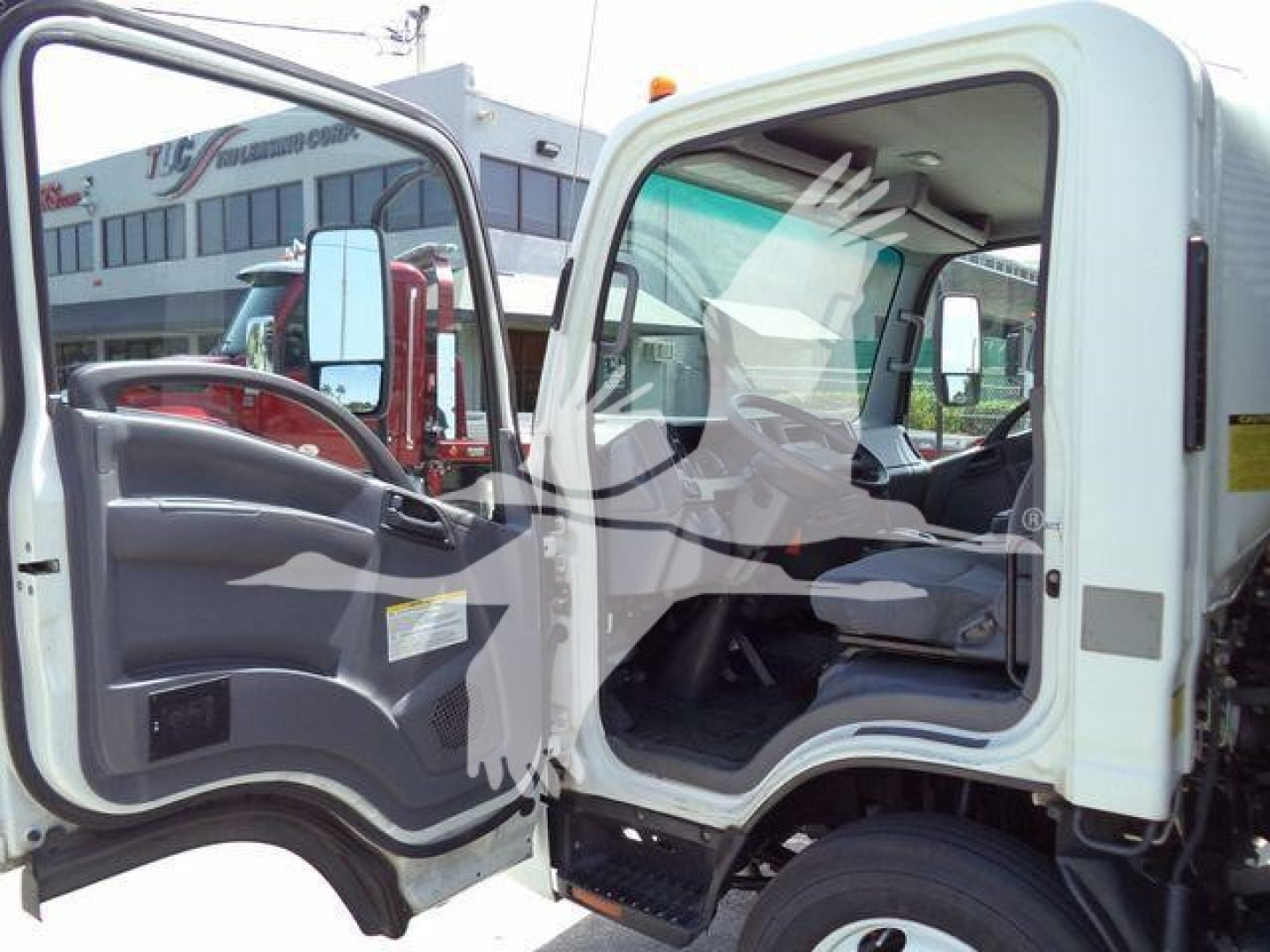 Isuzu NPR/NRR cab interior view with open driver door and view of dashboard; light-colored cab on a flatbed/dump truck.