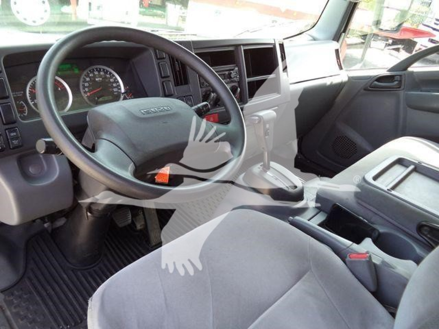 Isuzu NPRR cabin interior showing steering wheel, driver's seat, dashboard, and center console in a flatbed dump truck.