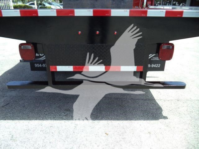Rear view of a 2019 Isuzu NRR flatbed dump truck showing taillights, reflective strip, and bumper with stock number T00722.