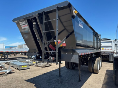 Ranco Anvil steel quarter-frame end dump trailer with black finish, dual rear wheels, hydraulic hoist, and a front hitch area visible.