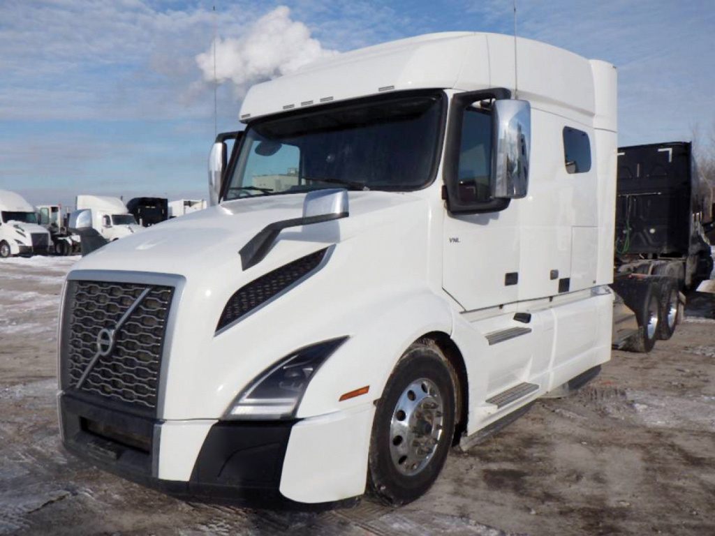 Volvo VNL 740 conventional sleeper truck in white, front three-quarter view showing large grille, aerodynamic mirrors, and side exhaust.