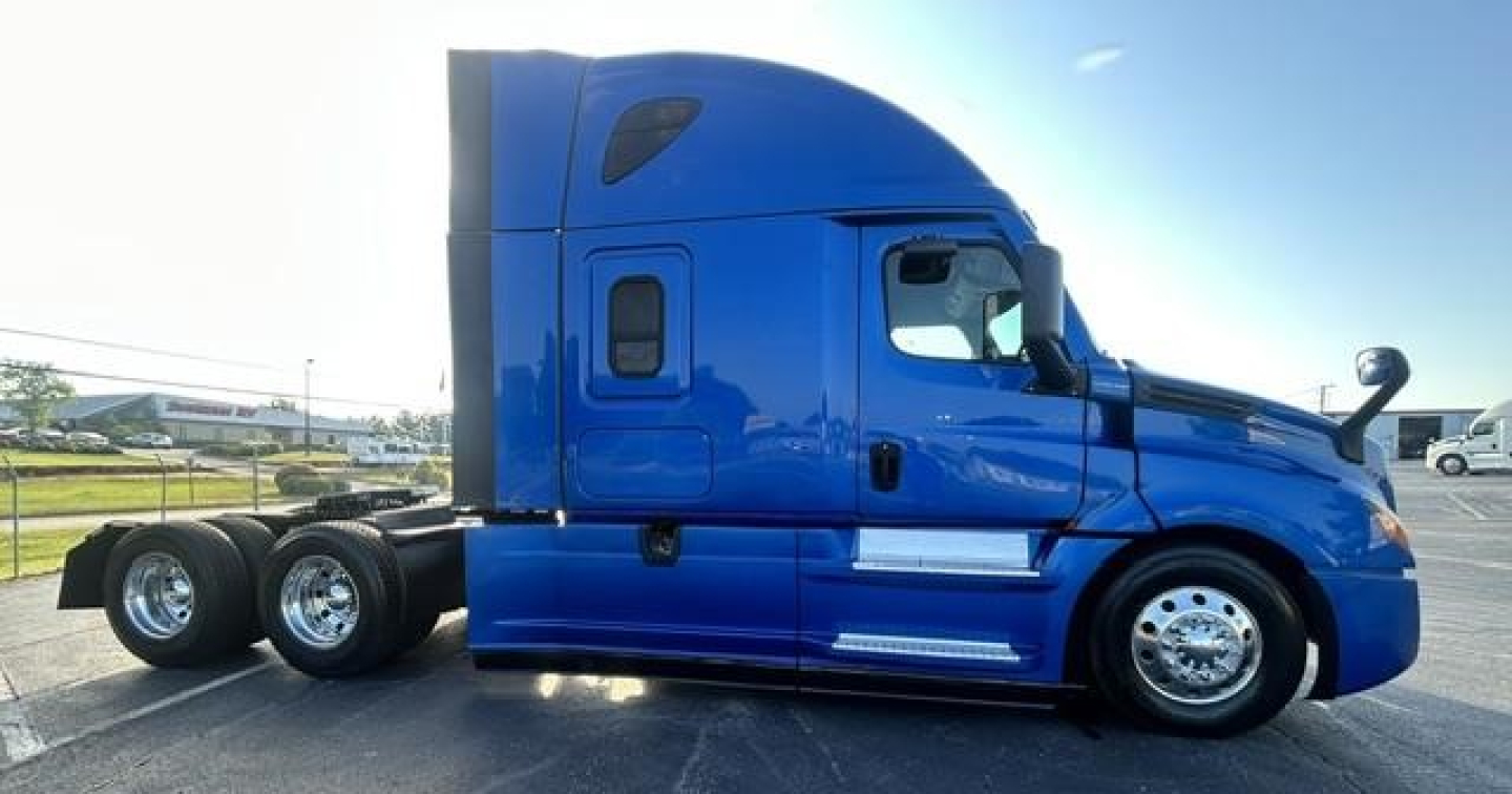 Freightliner Cascadia 126 sleeper cab side profile showing blue exterior, chrome wheels, and tandem rear axles.