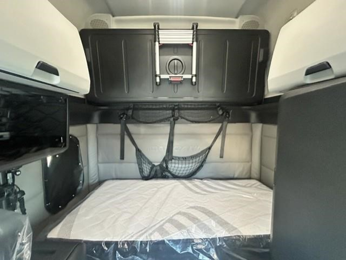 Freightliner Cascadia cab interior showing sleeper bed area with storage pouch and overhead compartments.