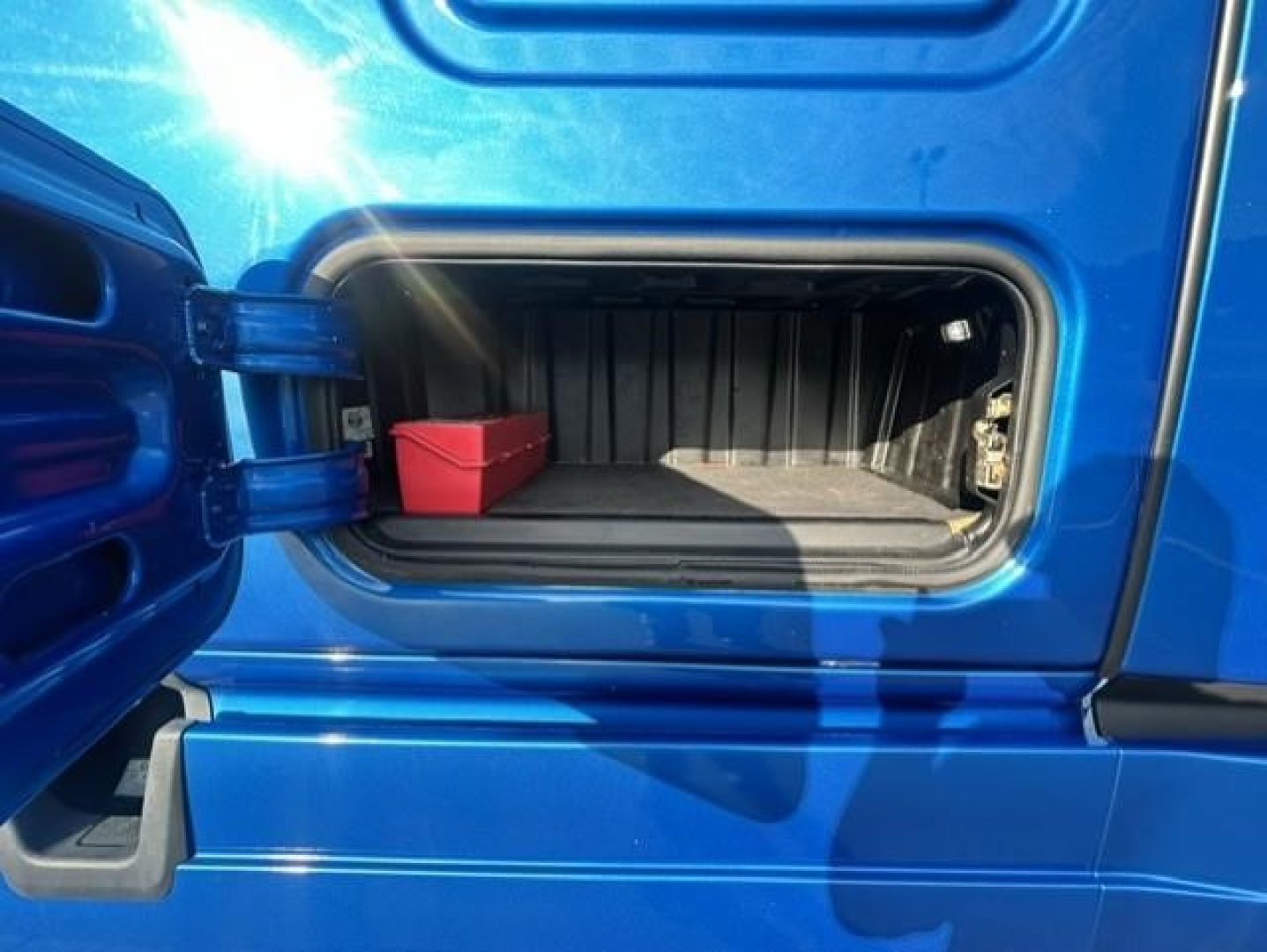 Freightliner Cascadia 126 sleeper truck exterior storage compartment with open side door showing a small red container inside