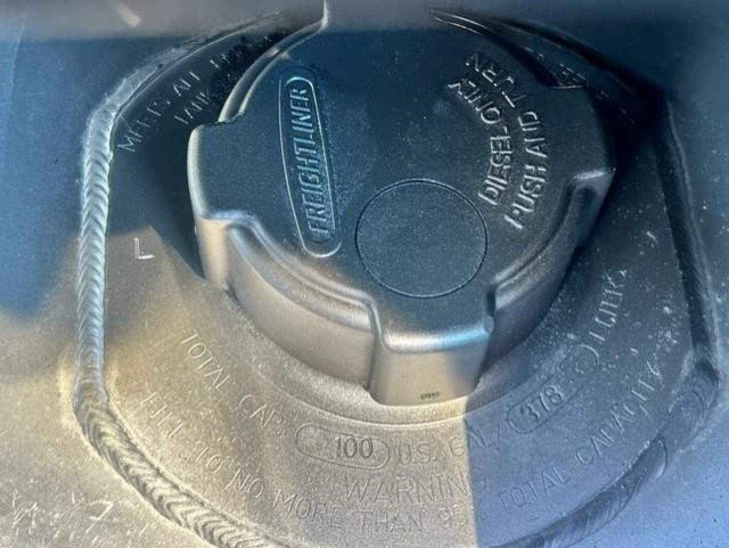 Cap with fuel/wuel tank? Circular locking cap with textured grip and surrounding labeling. Visible words include 'FUEL', 'OPEN', 'CLOSE', 'TANK', and '100' on the center ring.