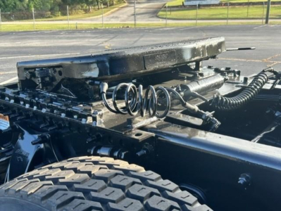 Truck chassis showing fuel tanks and suspension components with coil springs and wiring harness.