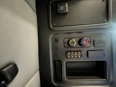 Dashboard panel of a Freightliner Cascadia 126 showing knobs, switches, and storage bay.