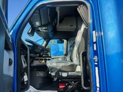 Truck cab interior of a 2022 Freightliner Cascadia 126 driver seat and dashboard visible through open door.