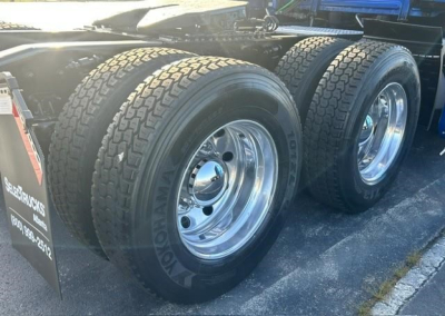 Freightliner Cascadia 126 dual rear axle with chrome wheels and Goodyear tires. Part of a sleeper truck chassis, visible fuel/air lines and wheel wells.