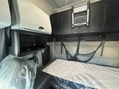 Freightliner Cascadia 126 sleeper cab interior showing bunk area with net storage and overhead cabinets.