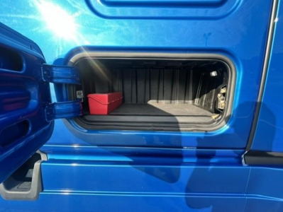 Freightliner Cascadia 126 sleeper truck exterior storage compartment with open side door showing a small red container inside