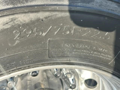 Tire sidewall with raised numbers 295/75R22.5 and a blank rectangular stamp area with serial text, part of wheel and rim visible.