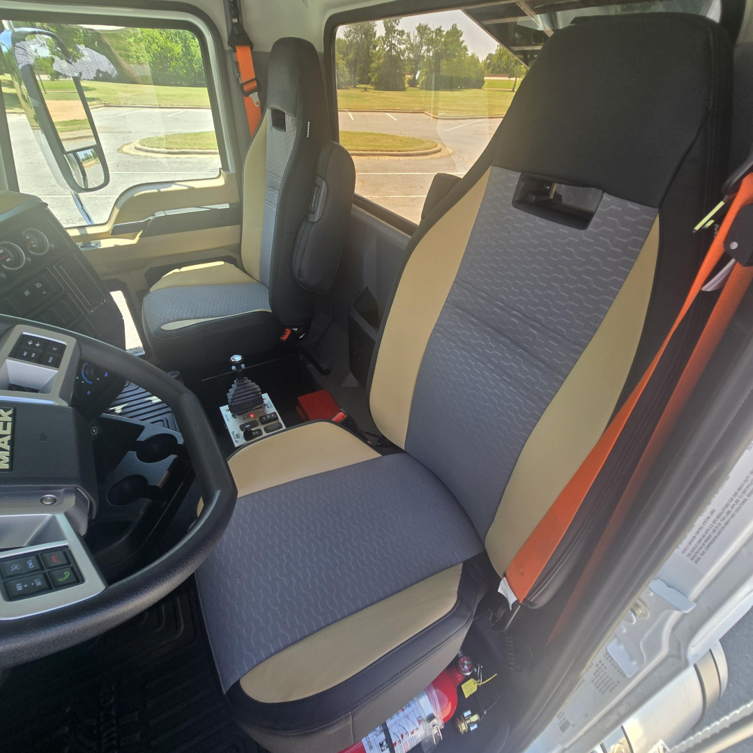 Mack PI64 cab interior showing driver and passenger seats with beige and gray upholstery and center console