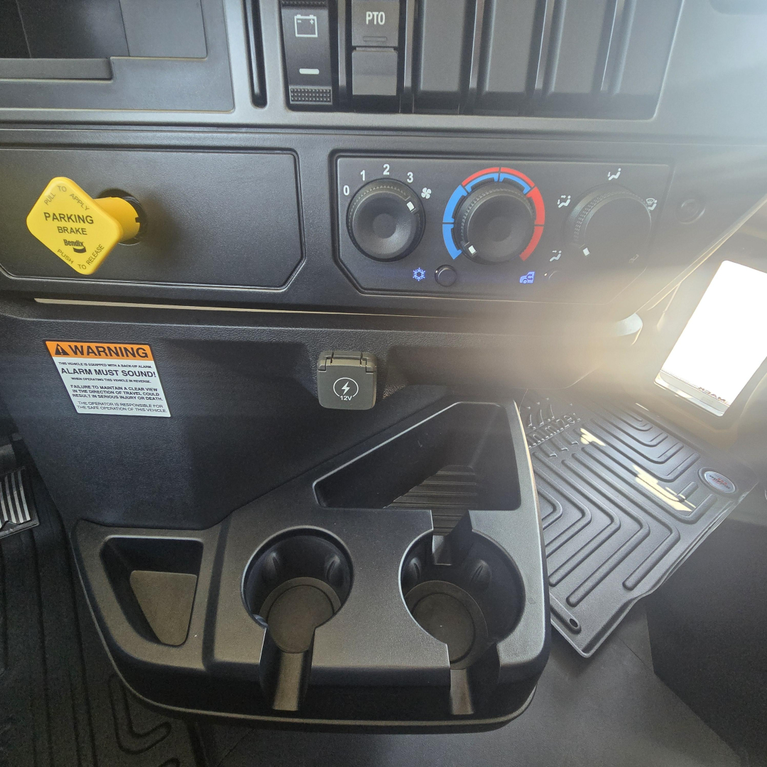 Dashboard of a 2026 Mack PI64 dump truck showing climate controls, ignition area, and cup holders with a yellow parking brake knob.