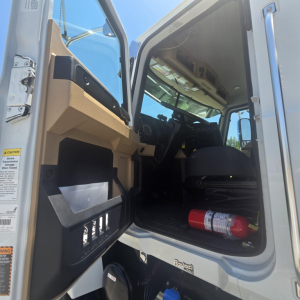 Cab interior of a 2026 Mack PI64 dump truck showing open driver door and dashboard area.