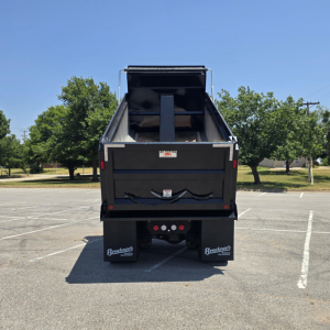 Dump truck bed of a 2026 Mack PI64 rear view showing dump cargo bed and taillights.