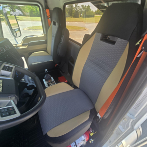 Mack PI64 cab interior showing driver and passenger seats with beige and gray upholstery and center console