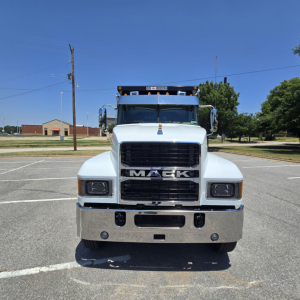 Front view of a white 2026 Mack PI64 dump truck showing large grille with MACK emblem and bumper, clear headlights, chrome bumper, and elevated cab.