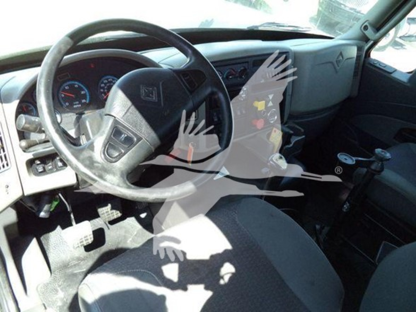 Truck cab interior showing steering wheel, dashboard, and driver seat with pedals visible.