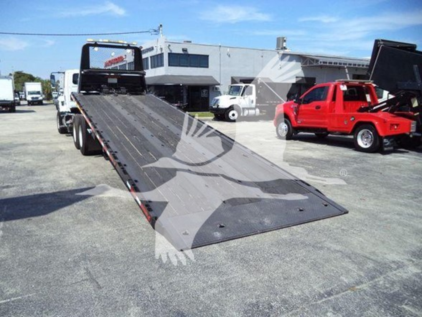2016 International Workstar 7600 rollback tow truck with a raised flatbed in the foreground. Visible text on the image includes VIN and stock details elsewhere, not on the truck itself.
