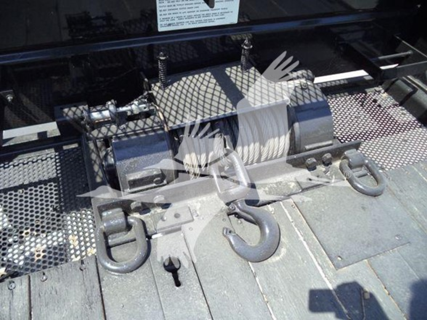 Truck bed equipment showing hooks, winch, and metal hardware in a roll-back truck. Visible text not legible.