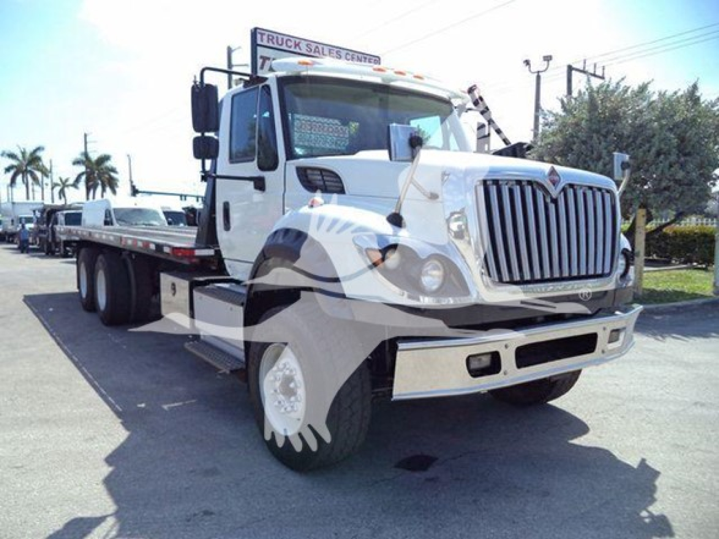 Truck bow-tie International Workstar 7600 rollback bed front view with white cab and chrome grille.