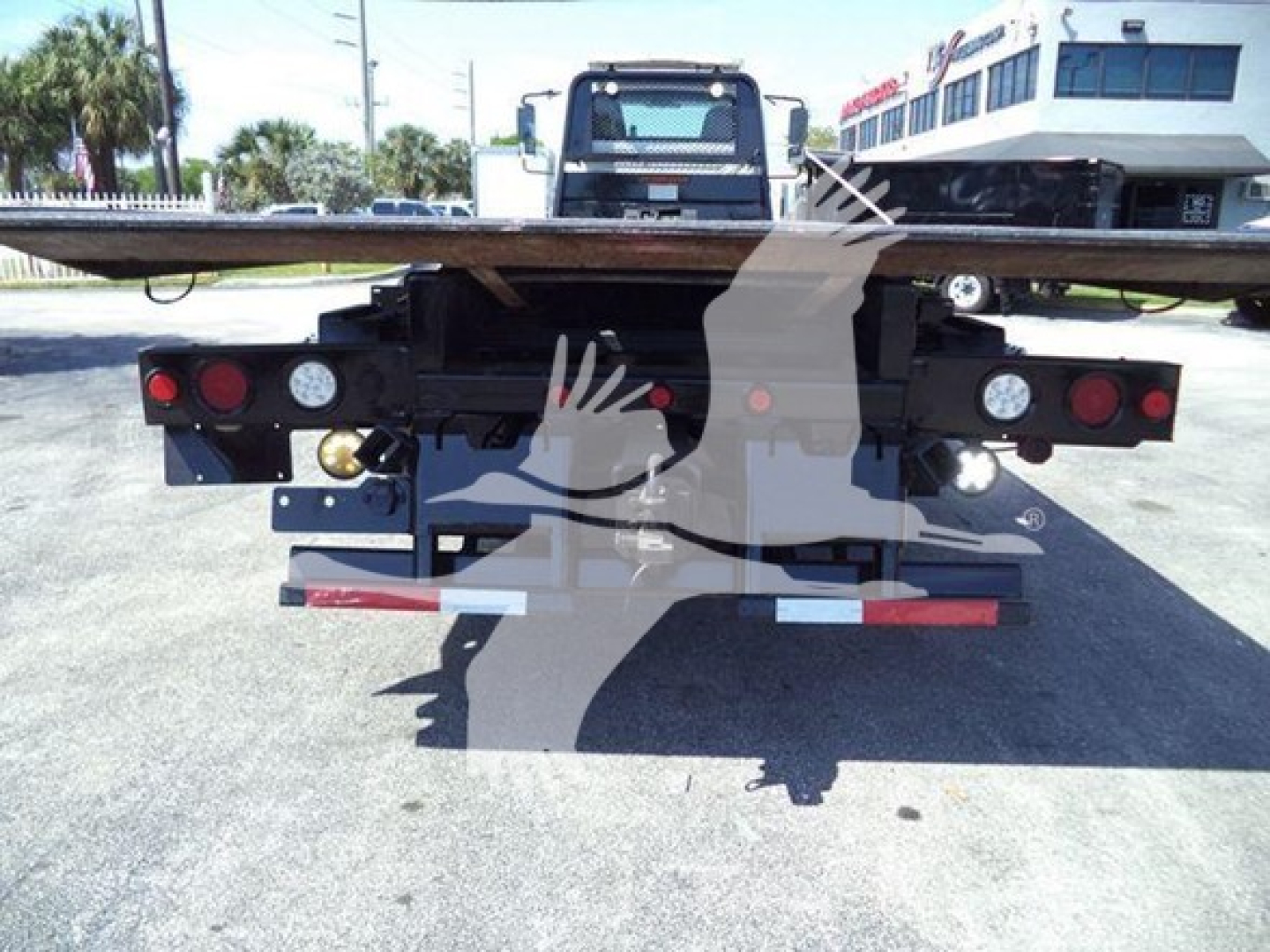 Rear view of a rollback tow truck bed with taillights, bumper, and platform; no legible text visible on components.