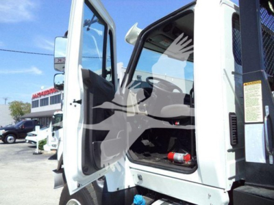 Truck cab interior with open driver door of a white 2016 International Workstar 7600 rollback truck showing dashboard and steering wheel.