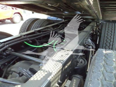 Trucks chassis underside view showing heavy-duty suspension and frame near rear wheels; green hoses and mechanical components visible under the cab.