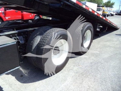Truck bed with dual rear axles of a 2016 International Workstar 7600 rollback trailer showing large wheels and undercarriage components.