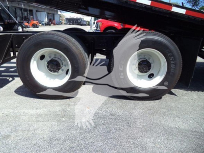 Dual rear wheels of a rollback truck undercarriage showing white steel rims and label text on tires.