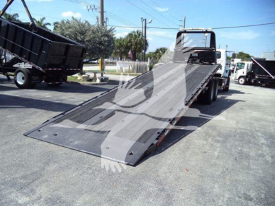 International Workstar 7600 rollback truck with a Deployable flatbed ramp in a parking lot.