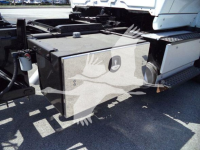 Truck chassis area showing large rectangular fuel or battery box mounted under a cab with steps and side rail; visible components include a hydraulic line and mounting brackets.