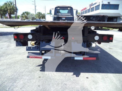 Rear view of a rollback tow truck bed with taillights, bumper, and platform; no legible text visible on components.