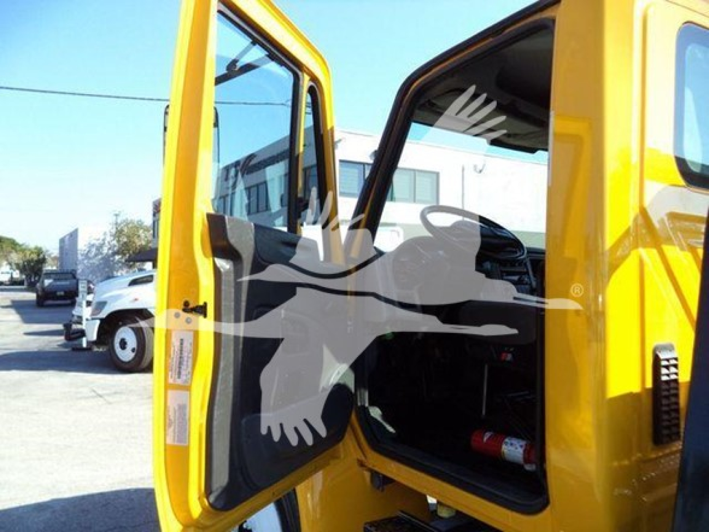 Truck cab interior with open doors of a yellow 2019 International 4300 auto carrier showing driver area and seat.